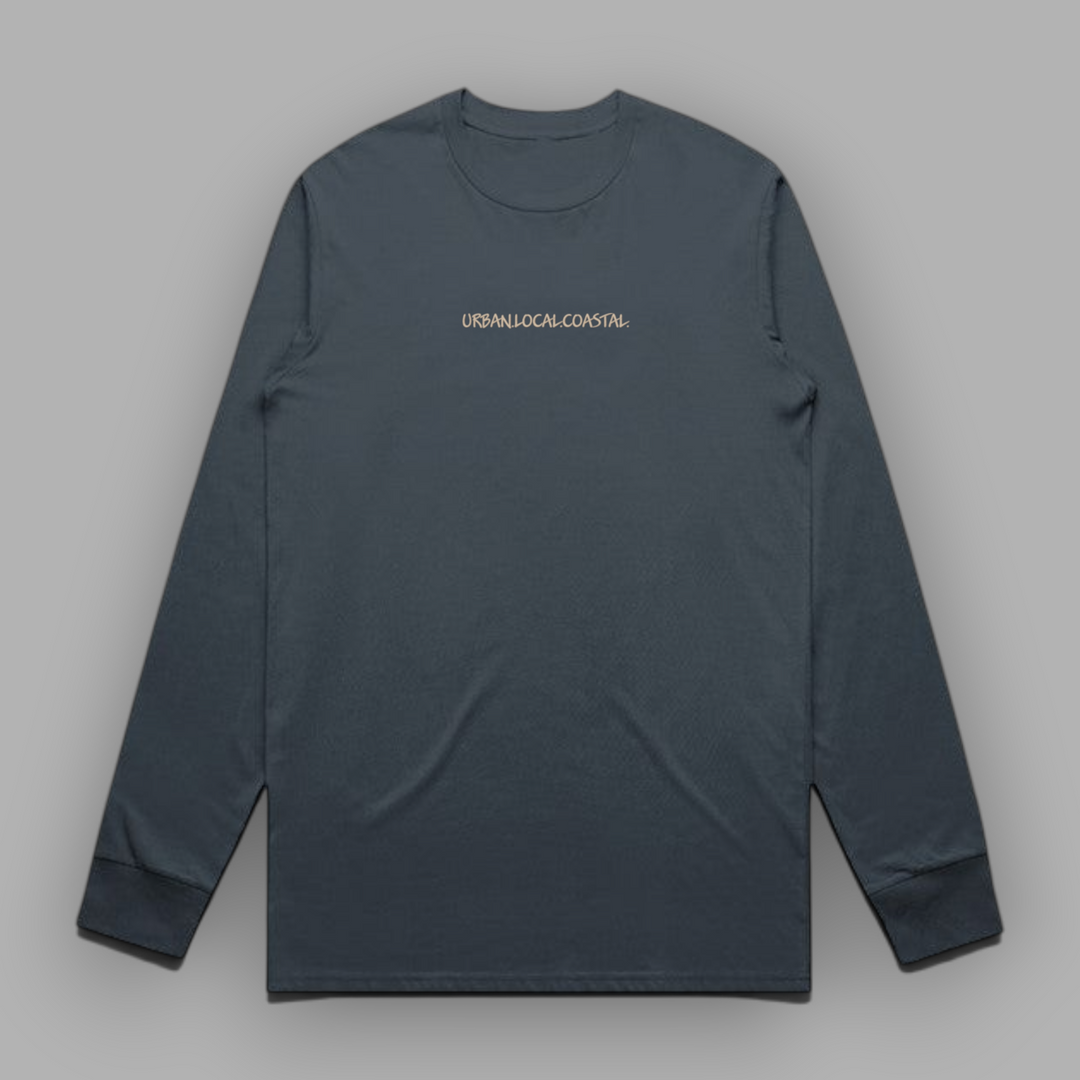 Front view of a petrol blue long-sleeve cotton tee with sand-colored URBAN.LOCAL.COASTAL. embroidery centered on the chest.