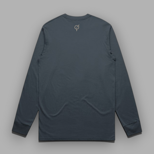 Back view of a petrol blue long-sleeve cotton tee with the signature Core Emblem embroidered in sand-colored thread below the back collar.
