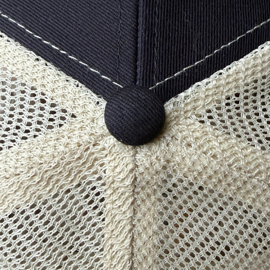 Close-up of area 609 The Core Trucker hat featuring black organic cotton panels and oyster recycled mesh back.