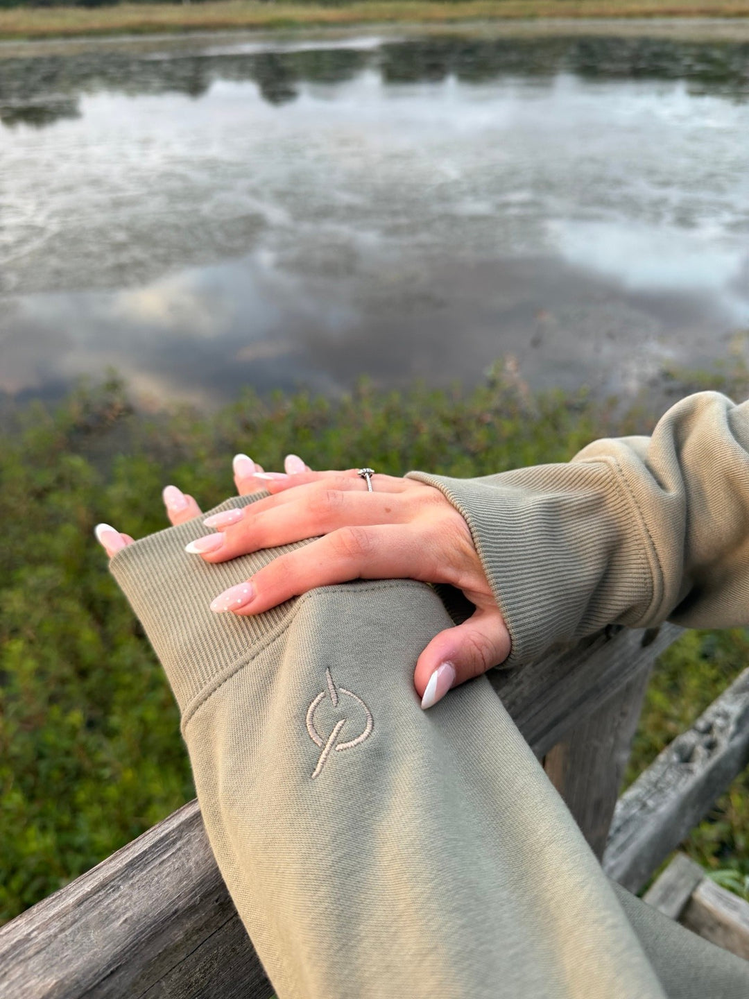 area 609 eucalyptus heavyweight fleece sweatshirt with signature sand embroidery on the cuff, outdoor lake setting
