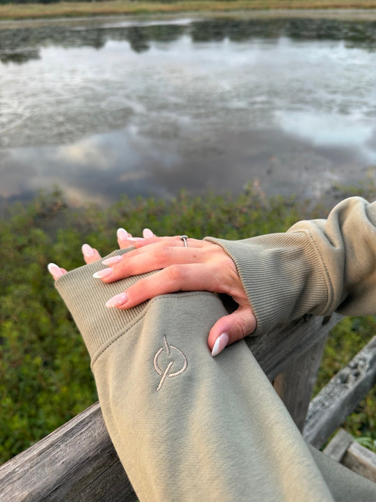 area 609 eucalyptus heavyweight fleece sweatshirt with signature sand embroidery on the cuff, outdoor lake setting
