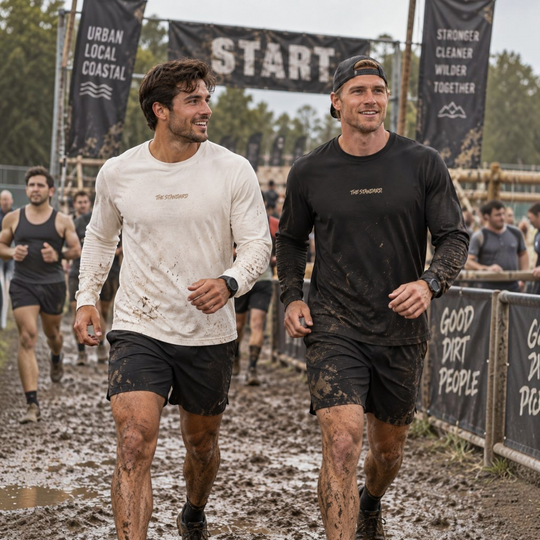 Two men wearing area 609 The Standard long sleeve Supima shirts in white and black during a muddy obstacle course race.